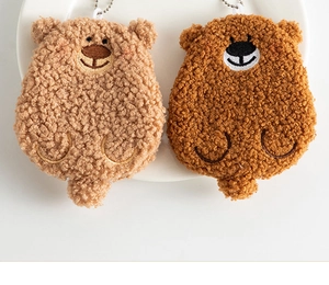 Close-up of brown plush teddy bear coin purses with metal chains on a white plate