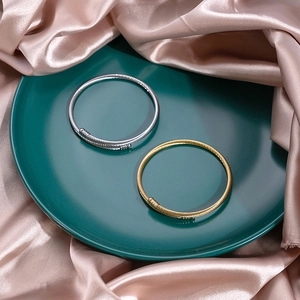 Detail of twisted metal rope bangles in gold and silver finish on silk fabric
