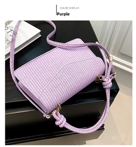 Detail of purple woven crossbody bag with gold hardware and adjustable strap on display