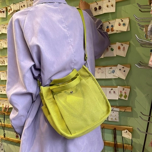 Bright green canvas tote bag with adjustable shoulder strap shown in a casual lifestyle setting