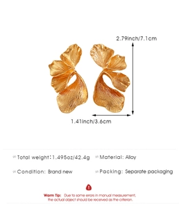 Detailed view of oversized golden leaf earrings in brushed alloy with size measurements