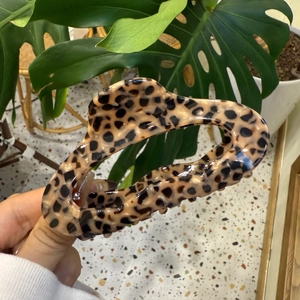 Leopard print hair claw clip in resin finish for thick hair shown in a hand-held view