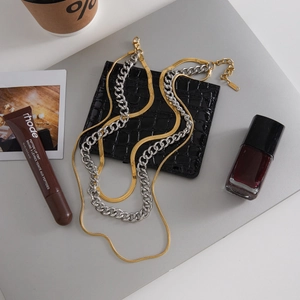 Layered gold snake chain and silver Cuban link necklace set with black clutch bag