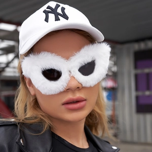 Close-up of oversized cat-eye sunglasses with white faux fur trim and dark lenses