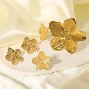 Detail view of gold floral cuff bracelet and earrings set with brushed metal texture