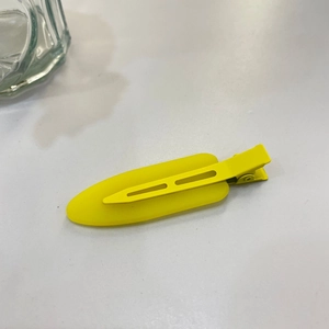Close-up of a matte lemon yellow hair clip with a seamless metal duckbill design