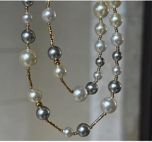 Detailed close-up of mixed white and grey high-luster pearls with gold hardware