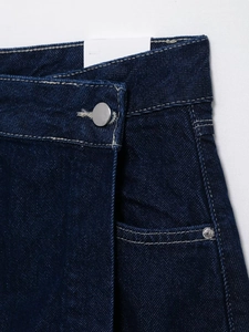 Detailed close-up of dark blue denim stitching, waistband buttons, and pocket craftsmanship
