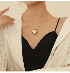 Close-up of a gold heart pendant necklace on a model showing fine jewelry details