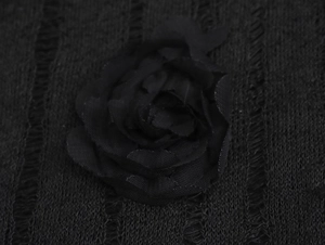 Gros plan sur le détail de la fleur 3D en tissu léger sur une robe en maille noire