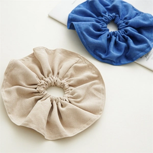 Detail of oversized beige and blue fabric scrunchies with a soft suede texture on a book