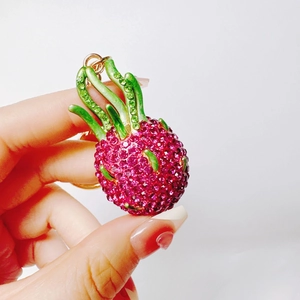 Close-up of a sparkling pink rhinestone dragon fruit keychain with green leaf details