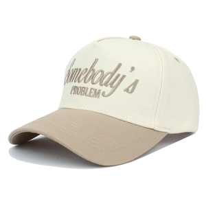Detail view of Somebody's Problem embroidery on a beige and khaki trucker cap
