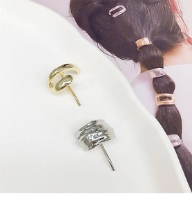 Detailed view of gold smooth round earrings and silver textured metal jewelry on a display stand