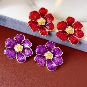 Primer plano de pendientes de flores vintage con pétalos rojos y morados y oro