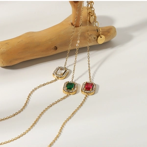 Detailed view of 18K gold plated bracelets with emerald, ruby, and crystal square charms