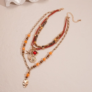 Detail of bohemian layered necklace with wooden beads, bow charm and metallic leaf pendant