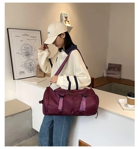 Detail of burgundy large capacity travel bag with purple straps in a lifestyle setting
