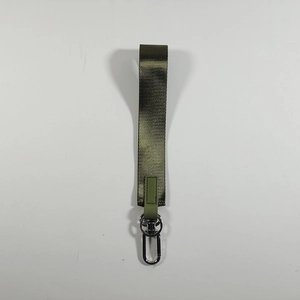 Dettaglio macro del portachiavi a cinturino in nylon verde militare con anello a D in metallo