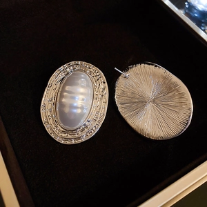 Macro detail of silver vintage oval pearl earrings showing textured front and back view