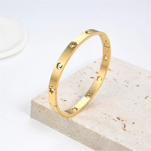 Detail of gold moon and star hollow stainless steel bangle on a frosted stone base