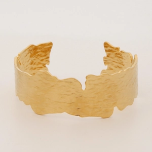 Close-up of golden wide open cuff bracelet with handcrafted hammered texture finish