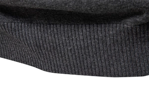 Vue macro des poignets côtelés et de la texture fine d'un pull en maille gris foncé
