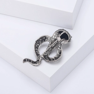 Vintage silver alloy snake brooch with rhinestones showing detailed back pin and texture