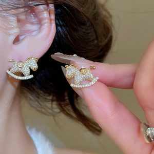 Close-up of golden horse earrings with clear crystals on model showing exquisite details