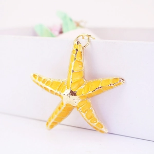 Macro detail of yellow starfish keychain with gold plating and smooth enamel finish