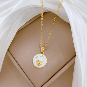 Golden MAMA heart necklace with white enamel pendant on white silk background