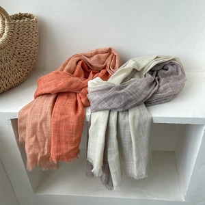Detail of gradient cotton linen scarves in orange and grey with fringed edges