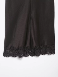 Détails de la jupe en satin noir avec dentelle délicate et fente sur l'ourlet