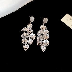 Macro detail of silver leaf earrings with round opal stone on a black background