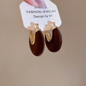 Close-up of vintage U-shaped earrings with brown flocking and gold metal finish
