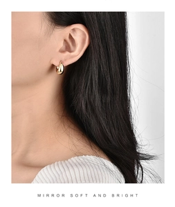 Detail showing the polished teardrop metal earring on model with mirror-like gold finish