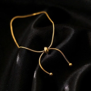 Adjustable 18K gold snake chain bracelet with polished slider on black silk background
