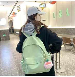 Light green nylon backpack with cute peach plush pendant shown on a model's back