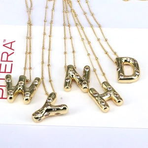 Detailed close-up of 18k gold-plated bubble letter pendants with sparkling cubic zirconia