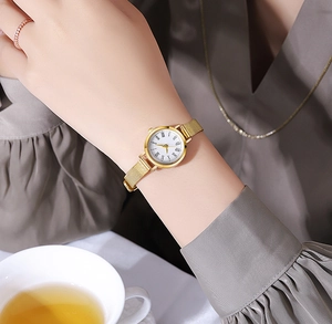 Detail of gold women's watch with Milanese mesh strap and elegant Roman numeral dial