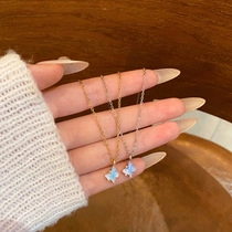 Detail of two vintage butterfly pendants in iridescent blue with gold and silver chains