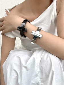 Close-up of wide T-shaped open cuffs in polished silver and black finish on a wrist