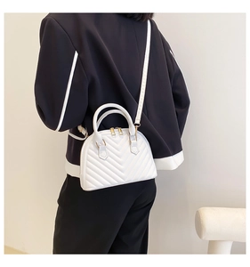 Close-up of white quilted leather crossbody bag with V-shaped stitching and gold hardware