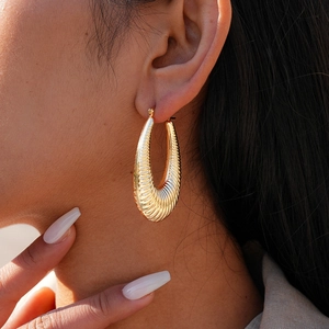 Close-up of thick gold-plated hoop earrings featuring a vintage textured spiral design