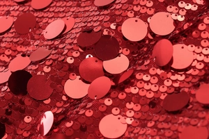 Macro shot of vibrant red sequins on mesh fabric showing light reflection and texture