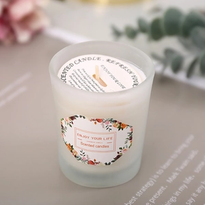 Minimalist scented soy candle in frosted glass jar with eucalyptus and dried flowers decor