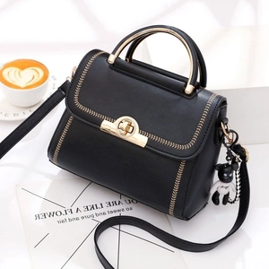 Fashionable black leather handbag with gold metal handle and cute bear charm pendant