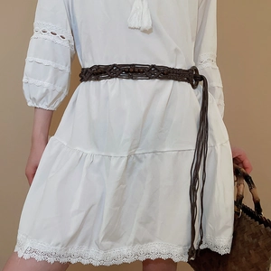 Detail of brown woven beaded waist belt with tassels on white lace dress
