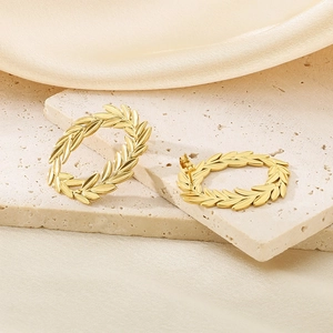Detail of 18k gold plated stainless steel leaf earrings on luxury silk and stone