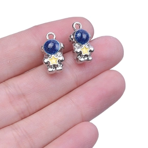 Silver astronaut pendants with blue glitter visors and stars, handheld for size